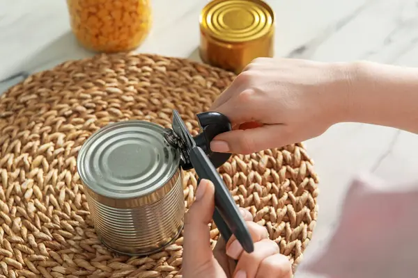 Beyaz mermer masada konserve açacağıyla konserve açan kadın, yakın plan.