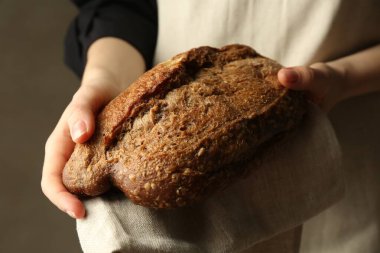 Gri arka planda taze ekmek somunu olan kadın, yakın plan.