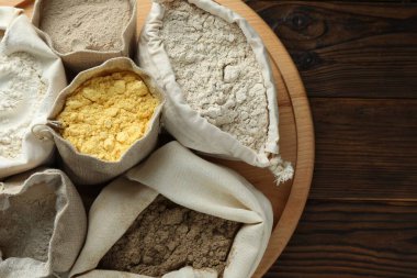 Tahta masadaki poşetlerdeki farklı un türleri, üst görünüm.