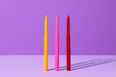 Mor arka planda renkli göz kalemleri, yakın plan