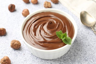 Lezzetli çikolata, naneli kase ve fındıklı gri desenli masa, yakın plan.