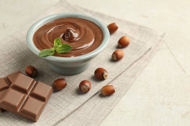 Lezzetli çikolata, parçalar, nane ve fındıklar ışık masasında, yakın plan