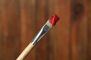 Ahşap arka planda kırmızı boyalı fırça, yakın plan.