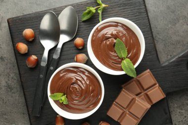 Lezzetli çikolata, parçalar, nane ve fındık, gri desenli masa, üst manzara.