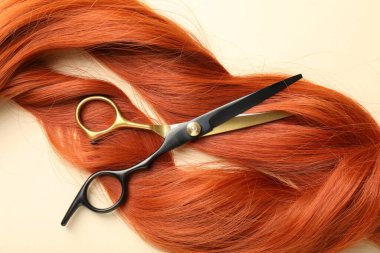 Bej arka planda saç kilitleri ve makas, düz yatış