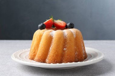 Açık gri masada pudra şekeri ve böğürtlenli Lezzetli kek, yakın plan.