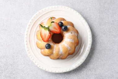 Açık gri masada pudra şekeri ve böğürtlenli Lezzetli Bundt keki.