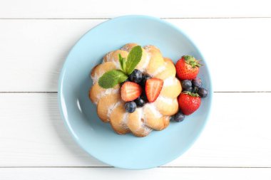 Beyaz ahşap masada pudra şekeri ve böğürtlenli Lezzetli kek.