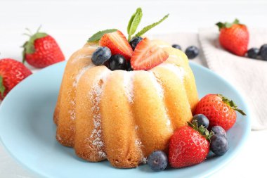 Beyaz masada pudra şekeri ve böğürtlenli leziz kek, yakın plan.