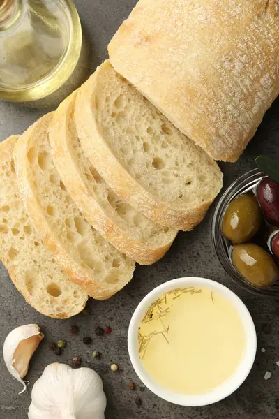 Yağ, zeytin ve baharatlı dilimlenmiş ekmek siyah masada, düz yerde.
