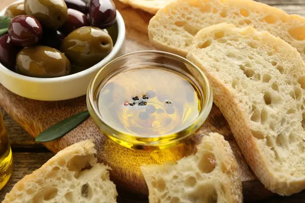 Yağlı ekmek dilimleri, ahşap masada baharatlar ve zeytinler, yakın plan.