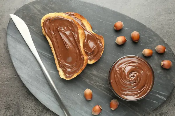 Lezzetli çikolatalı tostlar ve gri desenli masada fındıklar.