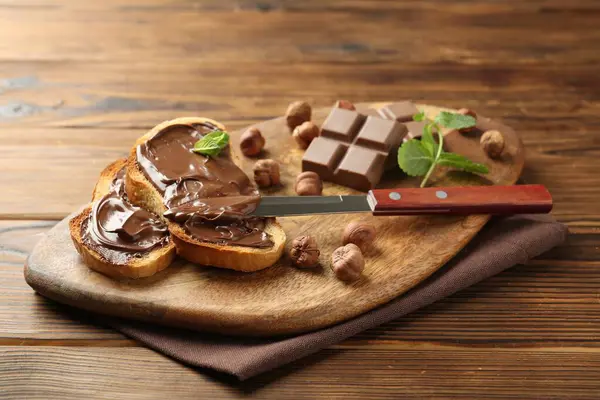 Lezzetli çikolatalı tostlar, parçalar, nane ve fındıklar ahşap masada, yakın plan.