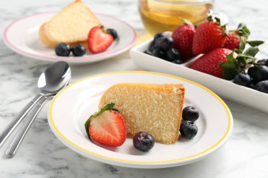 Lezzetli kek parçaları, böğürtlenli ve beyaz mermer masada çay, yakın plan.