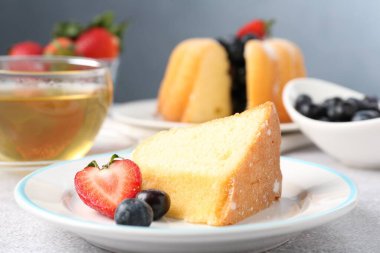 Açık gri masada böğürtlenli kek ve çay, yakın plan.