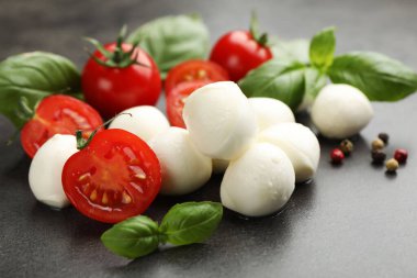 Mozzarella peyniri, domates, fesleğen ve biberler gri masada, yakın plan.