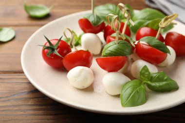 Ahşap masada mozarella, domates ve fesleğen ile aperatifler, yakın plan.