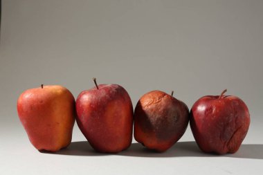 Açık gri arkaplanda hasarlı kırmızı elmalar