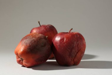 Açık gri arkaplanda hasarlı kırmızı elmalar