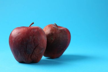 Açık mavi arkaplanda hasarlı kırmızı elmalar