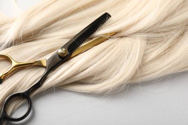 Sarı saç tokası ve makas açık gri arka planda, yakın plan.