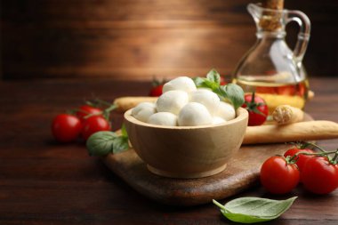 Lezzetli mozzarella peynir topları, ekmek çubukları, domates ve fesleğen ahşap masada, yakın plan.