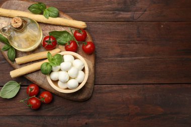 Lezzetli mozzarella peyniri topları, ekmek çubukları, domates ve fesleğen, ahşap masa, düz yatak. Metin için boşluk