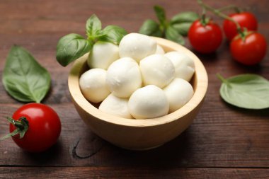 Lezzetli mozzarella peynir topları, domates ve fesleğen ahşap masada, yakın plan.