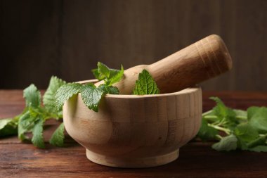 Taze limon merhemi yaprakları, ahşap masada tokmak ve havan topu, yakın plan.