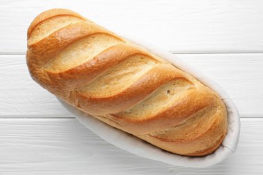 Beyaz ahşap masada, sepetin içinde bir ekmek somunu.
