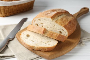 Beyaz ahşap masada ekmek ve bıçak kes, yakın plan.