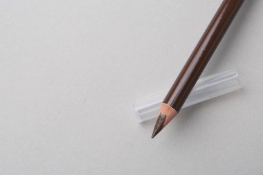 Açık arkaplanda kahverengi kaş kalemi, üst manzara. Metin için boşluk