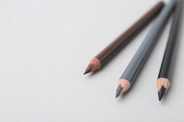 Arka planda üç farklı kaş kalemi, yakın plan. Metin için boşluk