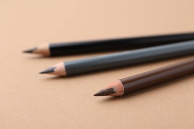 Bej arka planda üç farklı kaş kalemi, yakın plan.