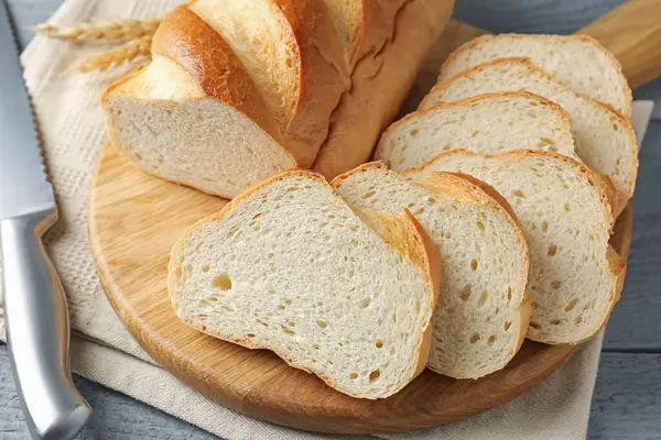 Gri ahşap masada dilimlenmiş ekmek ve bıçak, yakın plan.