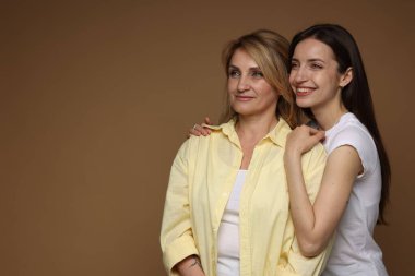 Açık kahverengi arka planda annesine sarılan bir kadın. Metin için boşluk