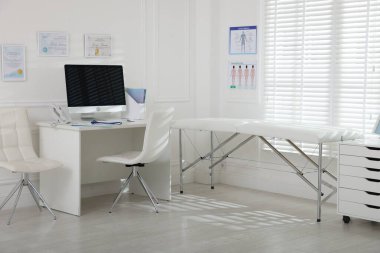 Tıp bürosunda modern bilgisayarlı ve muayene masalı bir doktorun çalışma yeri.