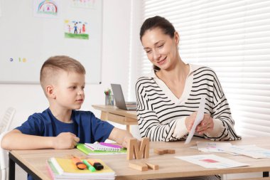 Okulda masa başında öğretmeniyle mektup öğrenen tatlı bir çocuk.