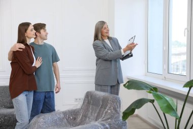 Gülümseyen emlakçı içeride çiftlere daire gösteriyor.