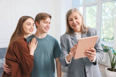 Tabletle gülümseyen emlakçı evde çiftlerle çalışıyor.