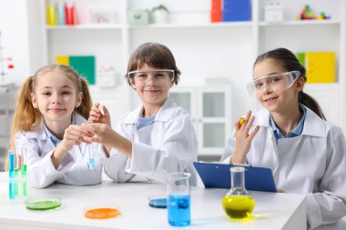 Çocuklar içeride masada kimyasal deneyler yapıyorlar.