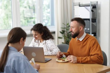 İş arkadaşları ofiste yemek yiyor ve sohbet ediyorlar.