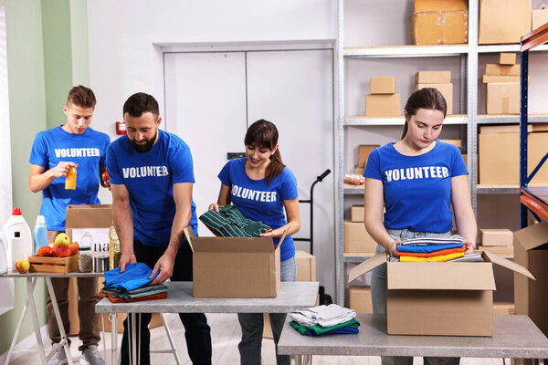 Group of volunteers packing donation goods at tables indoors