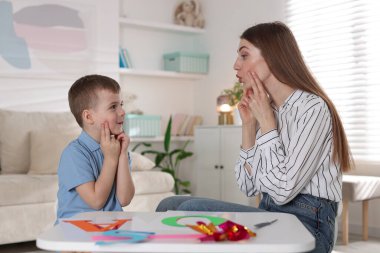 Küçük çocukla içeride çalışan bir konuşma terapisti.