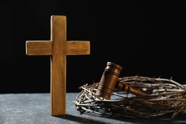 Dikenli taç, yargıç tokmağı ve koyu dokulu arka planda tahta haç.