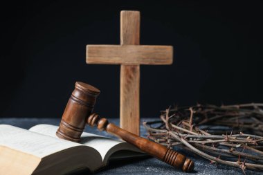 Dikenli taç, yargıç tokmağı, İncil ve koyu dokulu arka planda tahta haç.