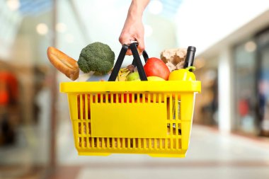 Süpermarkette elinde farklı gıda ürünleri olan bir adam var.