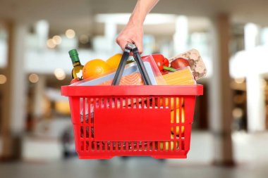 Süpermarkette elinde farklı gıda ürünleri olan bir adam var.