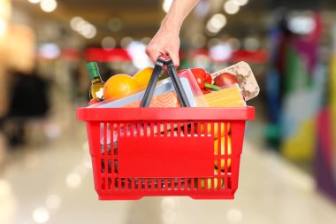 Süpermarkette elinde farklı gıda ürünleri olan bir adam var.