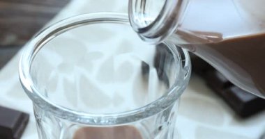 Çikolatalı sütü şişeden bardağa döküyorum.